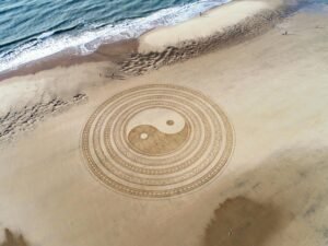 Aerial view of intricate Yin Yang design on La Tremblade beach sand